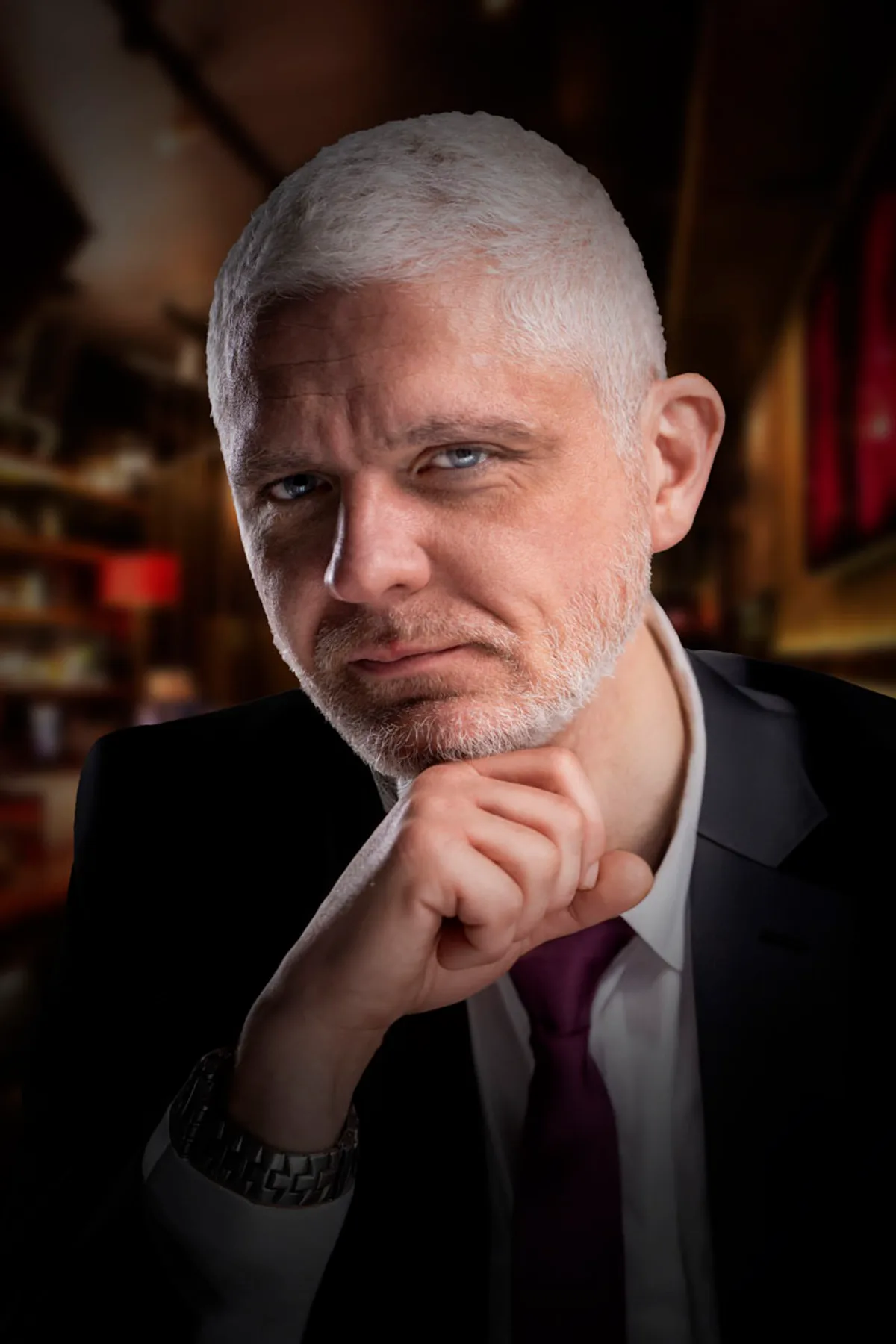 Dramatisks studijas portrets vīrietim ar baltiem matiem un bārdu, atbalstot zodu uz rokas