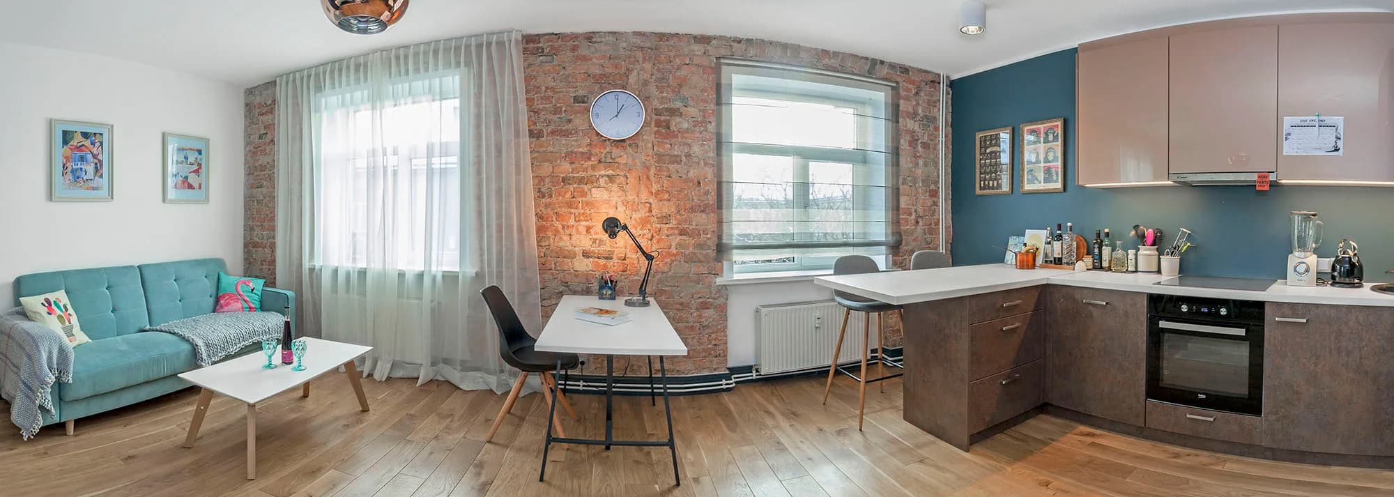 Panorāmas foto atklāta plāna dzīvojamai istabai un virtuvei ar ķieģeļu sienu
