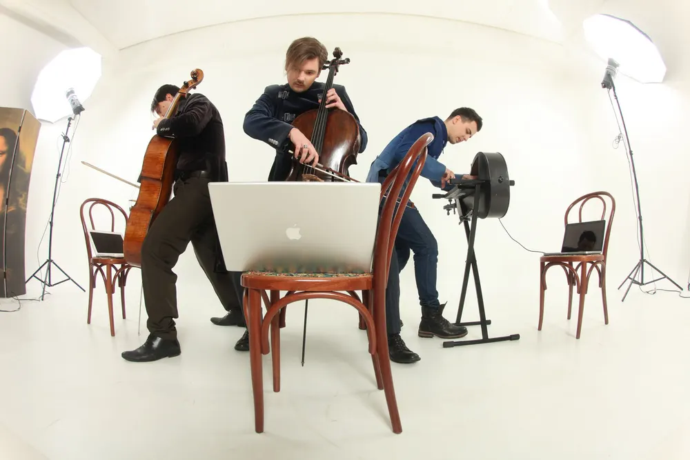 Cellists recording between takes surrounded by laptops and studio chairs