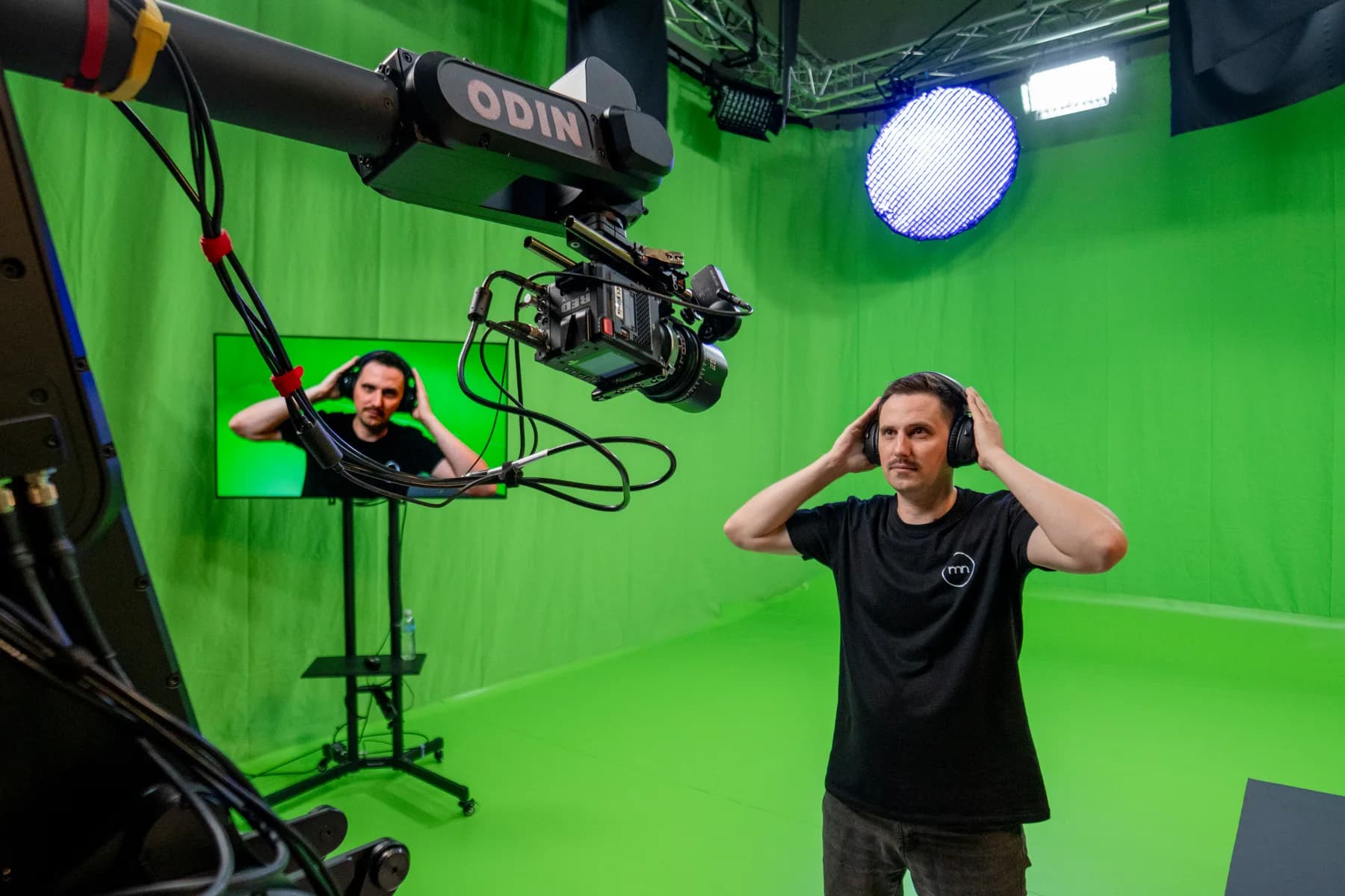 Robotic camera arm framing a presenter against a full chromakey cyclorama