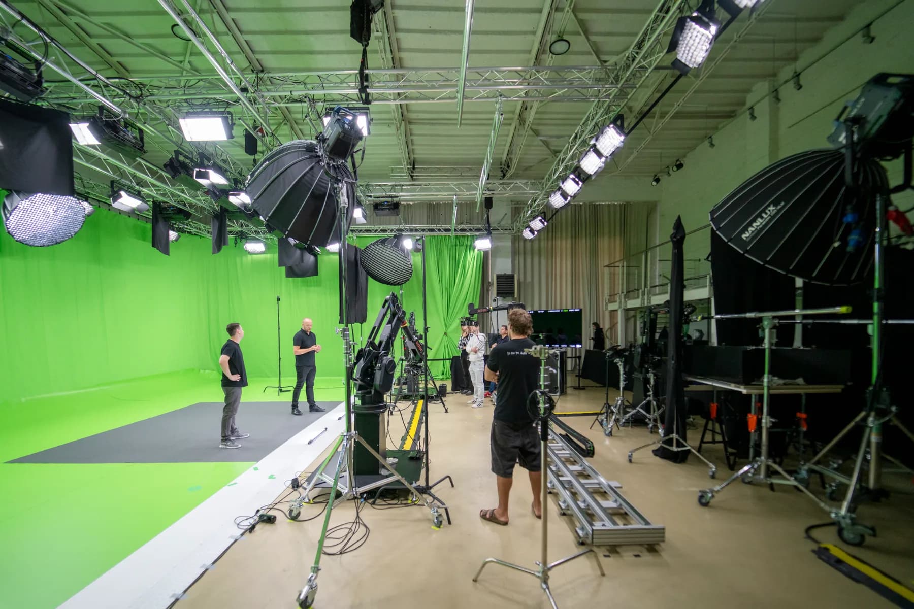 Camera operator filming on a tracking rig in a large chromakey studio