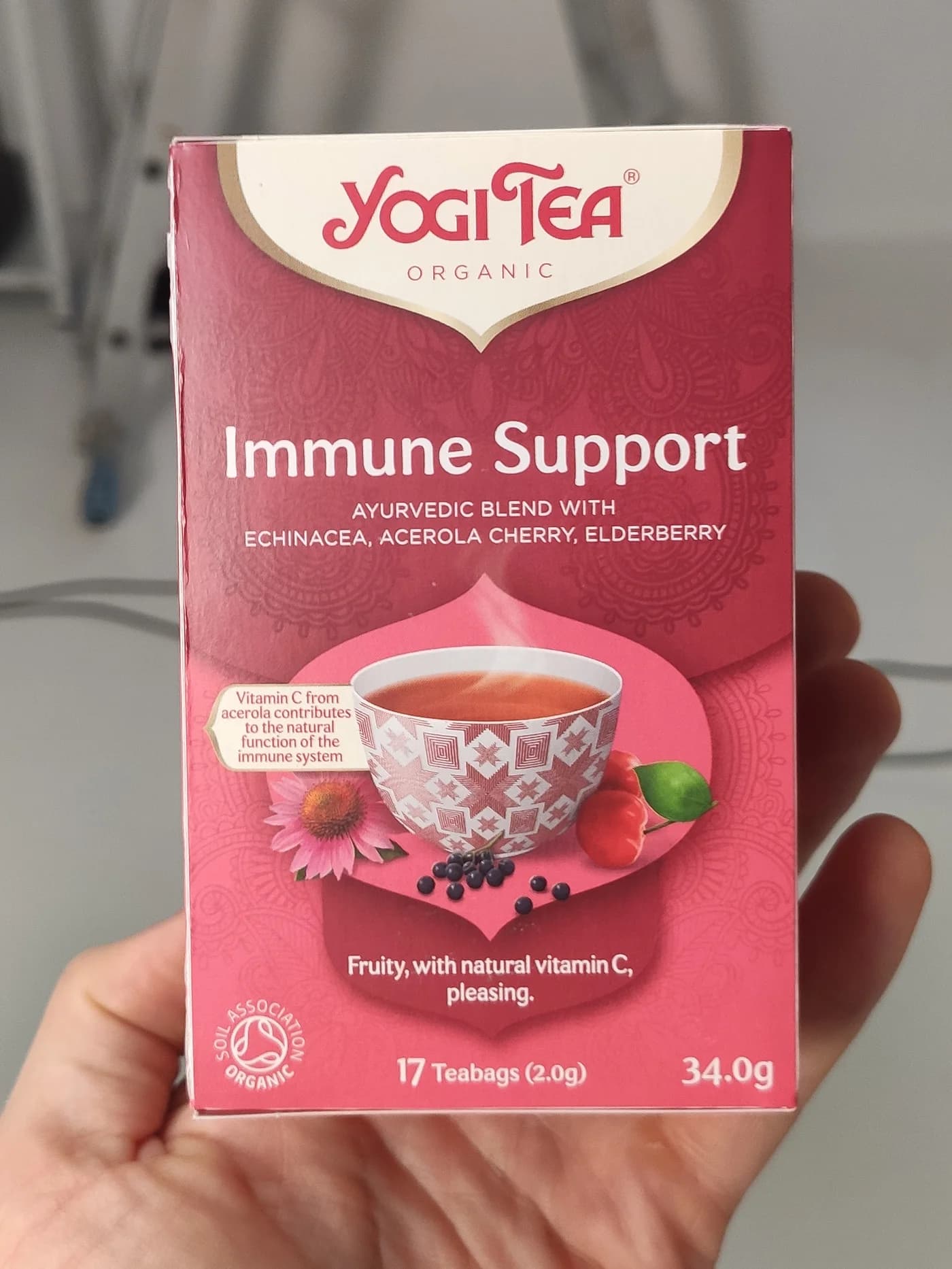 Oriģinālais vienkāršais produkta foto Yogi Tea Immune Support kastītei, turētai rokā