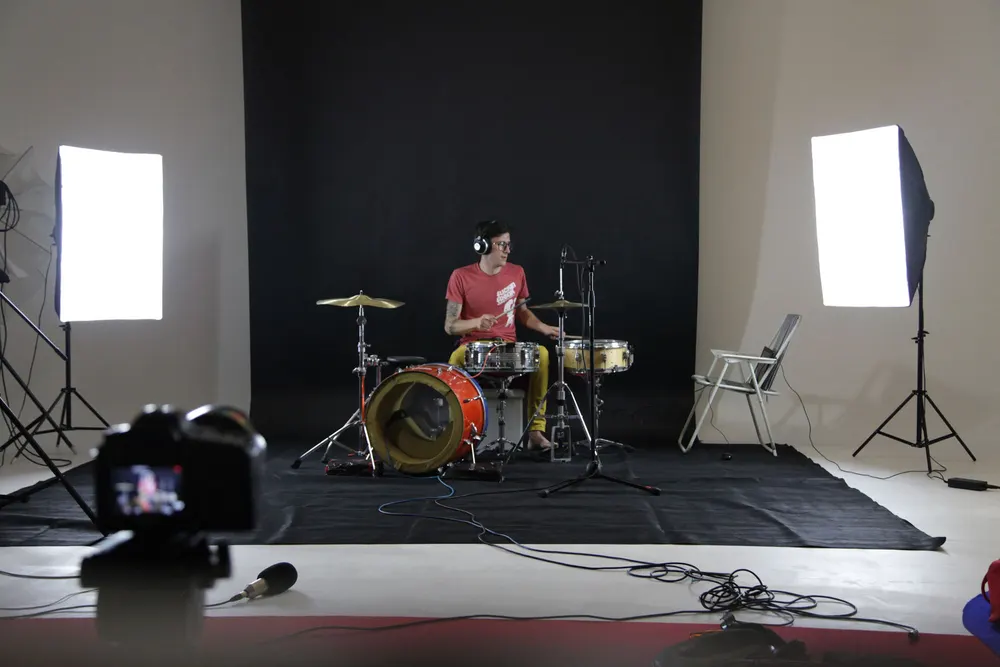 Drummer being filmed for a music video under studio softboxes